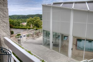 A balcony with a pool, outdoor seating, and a view of a green landscape. - Whispering Pines 321 (Pigeon Forge)