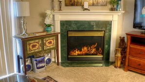A living room with a fireplace, a television, and a fireplace mantel with decorative items. - Whispering Pines 321 (Pigeon Forge)