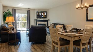 A living room with a fireplace, a dining table with chairs, a sofa, and a lamp. - Whispering Pines 333 (Pigeon Forge)