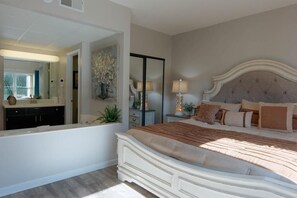 A bedroom with a large bed, a nightstand with a lamp, a mirror, and a dresser. - Whispering Pines 333 (Pigeon Forge)