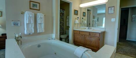 A bathroom with a large bathtub, wooden vanity, and a mirror.