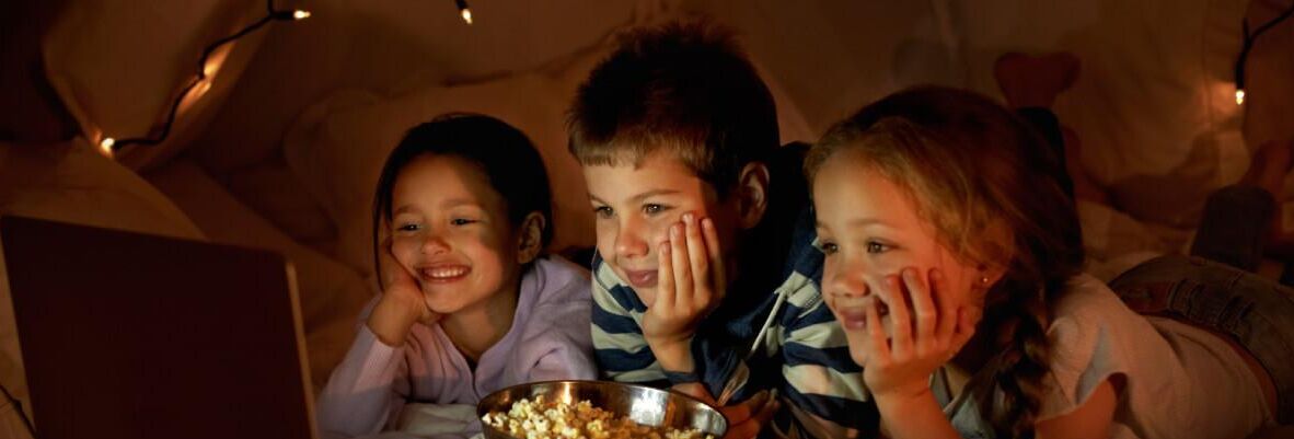 Een groepje kinderen zit dicht bij elkaar, met een schaal popcorn voor zich.