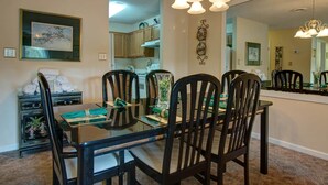 A dining area with a glass table, four chairs, and a chandelier. - Whispering Pines 354 (Pigeon Forge)