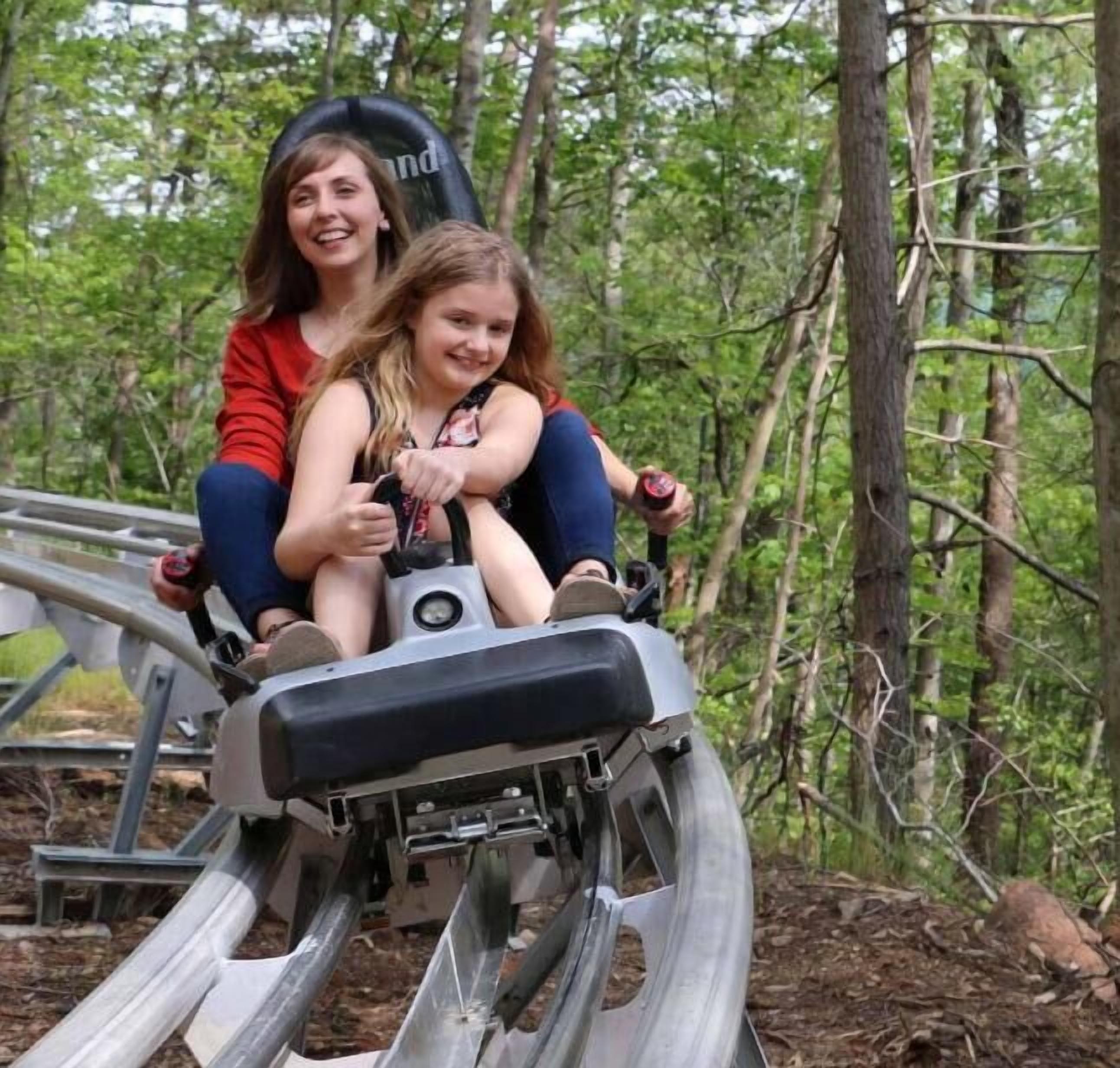 Zwei Personen fahren mit, Wald im Hintergrund.