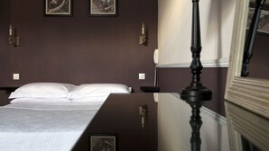 A hotel room with a bed, a nightstand, a lamp, and two framed pictures on the wall. - Villa Saint Hubert (Nice)