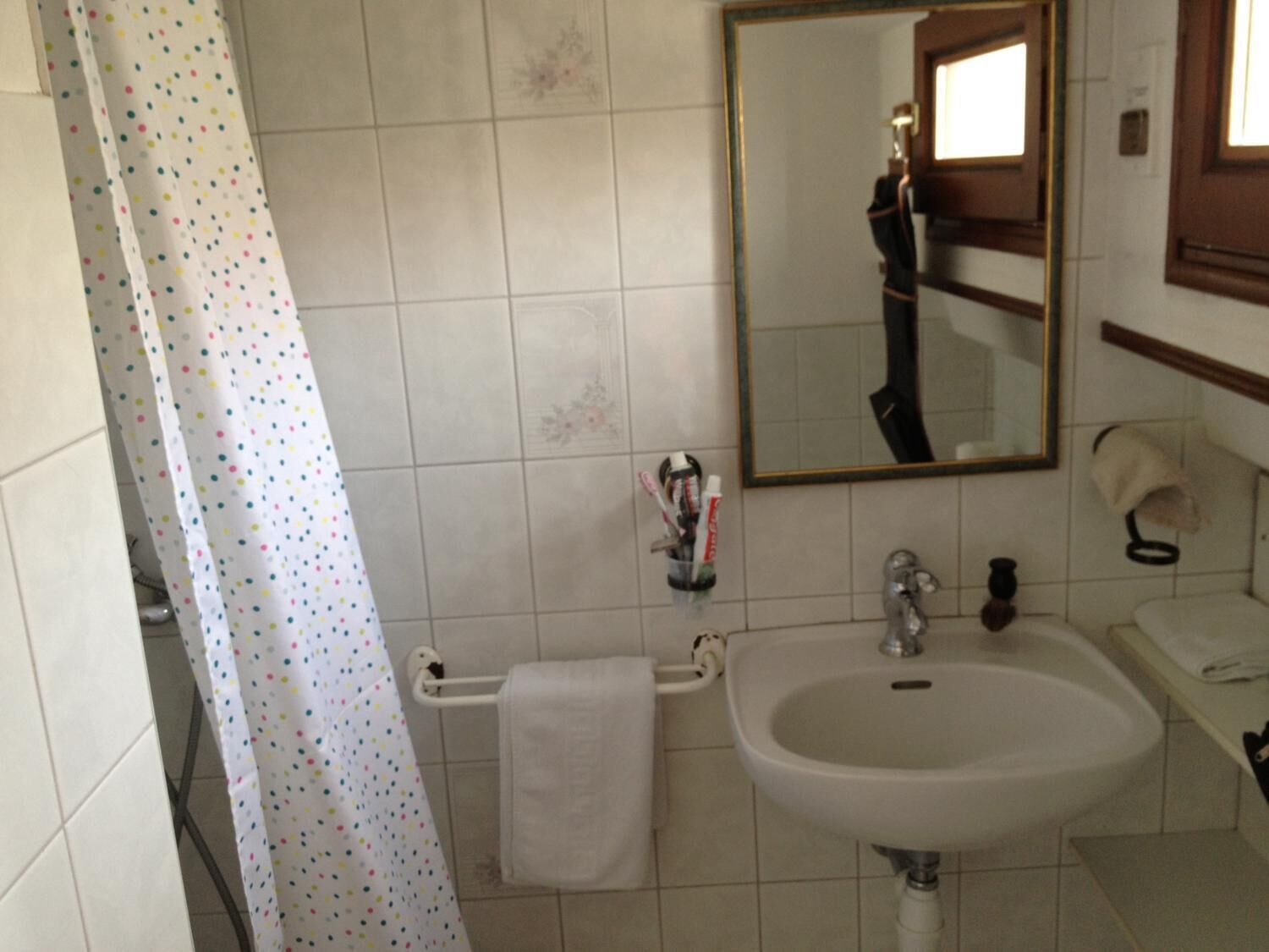 Een badkamer met een wit wastafel, een spiegel en een douchegordijn met stippen.