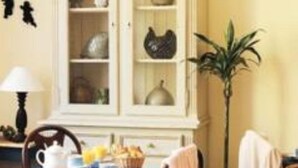 A dining area with a wooden table set for breakfast, a cabinet with dishes, and a potted plant. - Villa Saint Hubert (Nice)