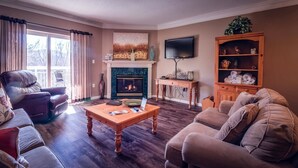 Uma sala de estar com lareira, televisão e um aparador de madeira com objetos decorativos.