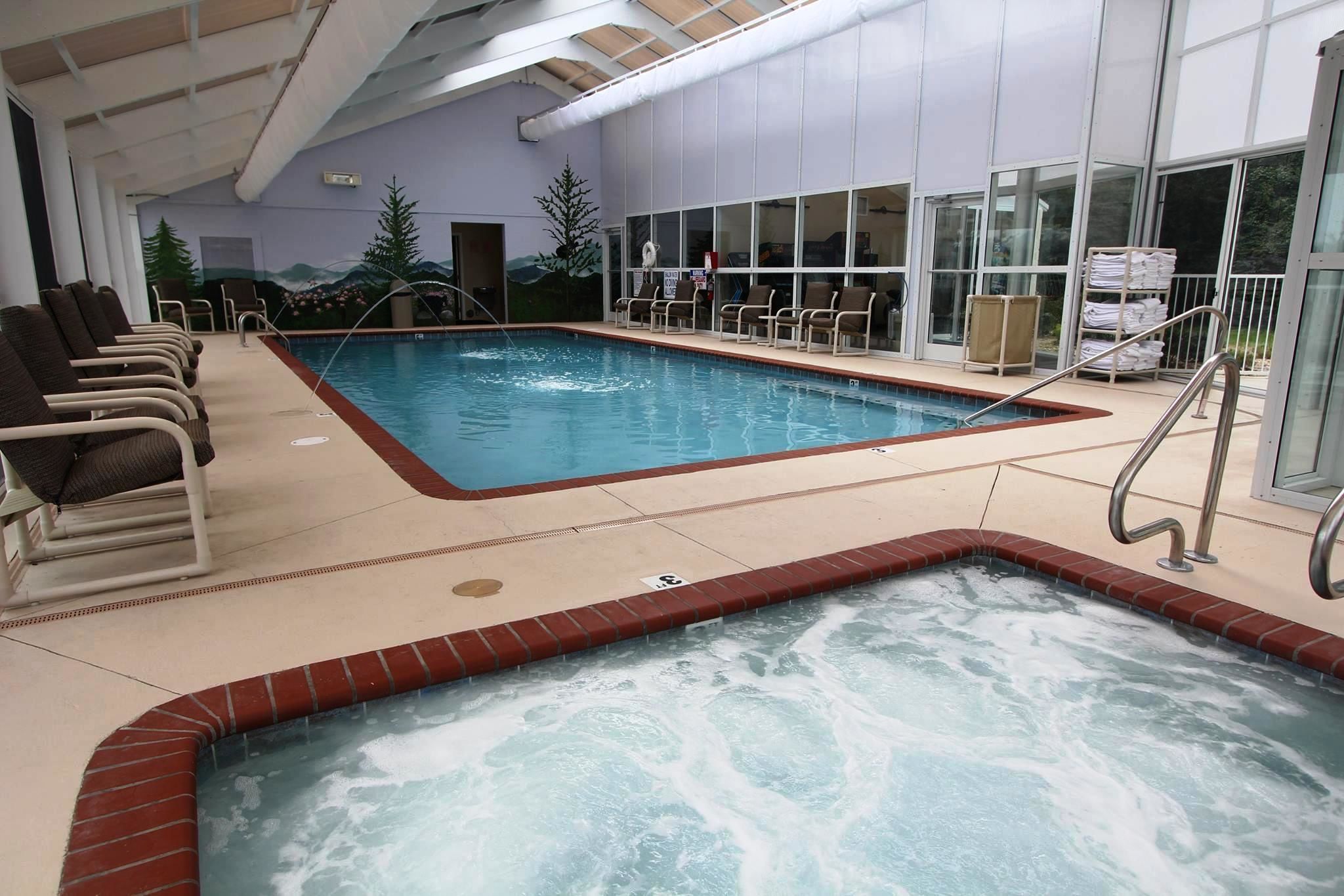 An indoor swimming pool with lounge chairs, a hot tub, and a mural on the wall.