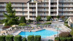 A hotel with a swimming pool, outdoor seating, and a parking lot. - Whispering Pines 322 (Pigeon Forge)