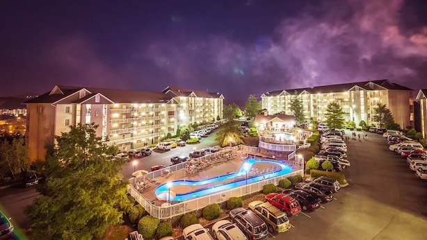 A hotel with multiple buildings, a swimming pool, and a parking lot. - Whispering Pines 322 (Pigeon Forge)