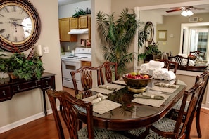 Enjoy meals in this inviting dining area with a round table, comfortable chairs, and a large potted plant.