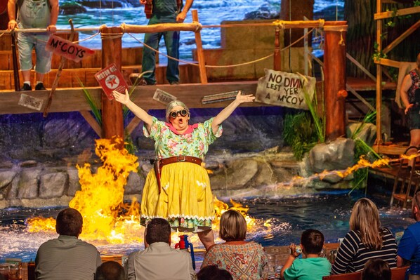 A performer on stage with a fire effect in the background.