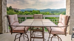 A covered patio with a table and chairs, overlooking a mountainous landscape. - Whispering Pines 441 (Pigeon Forge)