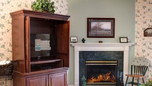 A living room with a fireplace, a wooden cabinet, and a framed picture on the wall. - Whispering Pines 421 (Pigeon Forge)