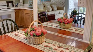 A dining table with a woven basket of red apples and a placemat with a fruit pattern. - Whispering Pines 421 (Pigeon Forge)