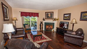 A living room with leather sofas, a fireplace, and framed pictures on the walls. - Whispering Pines 444 (Pigeon Forge)