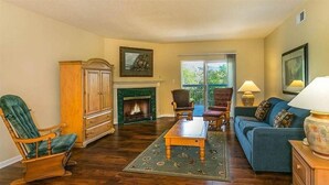 A living room with a fireplace, a sofa, a chair, and a lamp. - Whispering Pines 433 (Pigeon Forge)