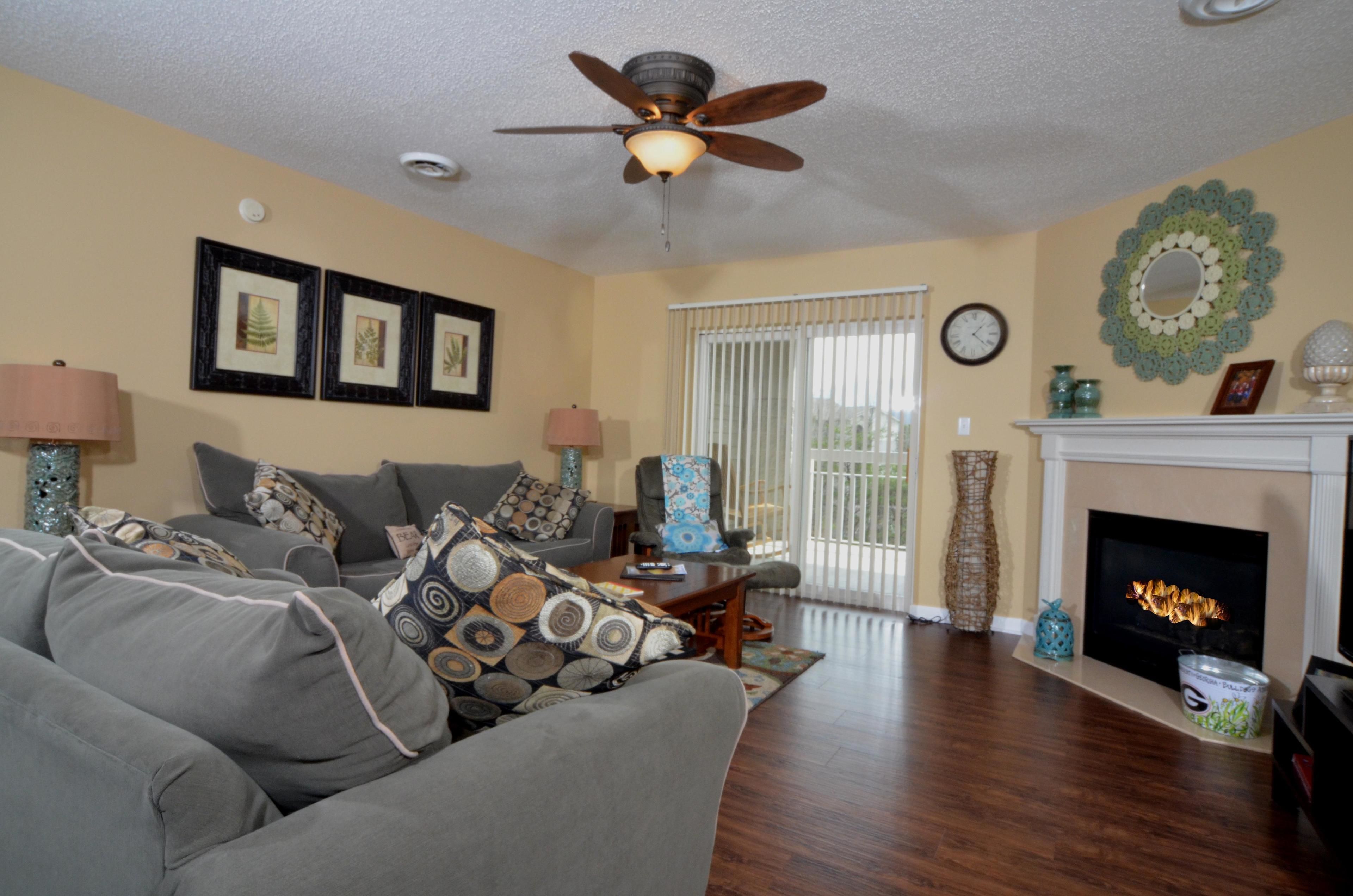A living room with a sofa, two lamps, a fireplace, and framed pictures on the wall.