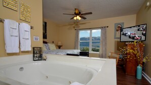 Camera d'albergo con una grande vasca da bagno, un ventilatore a soffitto, una televisione e vista sull'esterno.