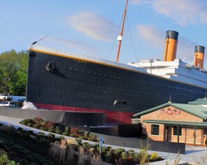 A large ship with the name 'Titanic' on its side, docked near a building with a sign that reads 'White Star'. - Whispering Pines 451 (Pigeon Forge)
