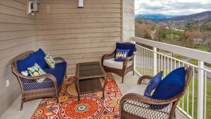 Un balcone con mobili in vimini, un tappeto decorato e vista su un paesaggio montuoso.