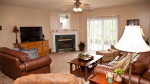 A living room with a fireplace, leather sofas, a television, and a ceiling fan. - Whispering Pines 514 (Pigeon Forge)