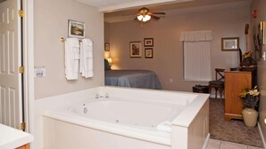 A bathroom with a large bathtub, a ceiling fan, and a window with blinds. - Whispering Pines 514 (Pigeon Forge)