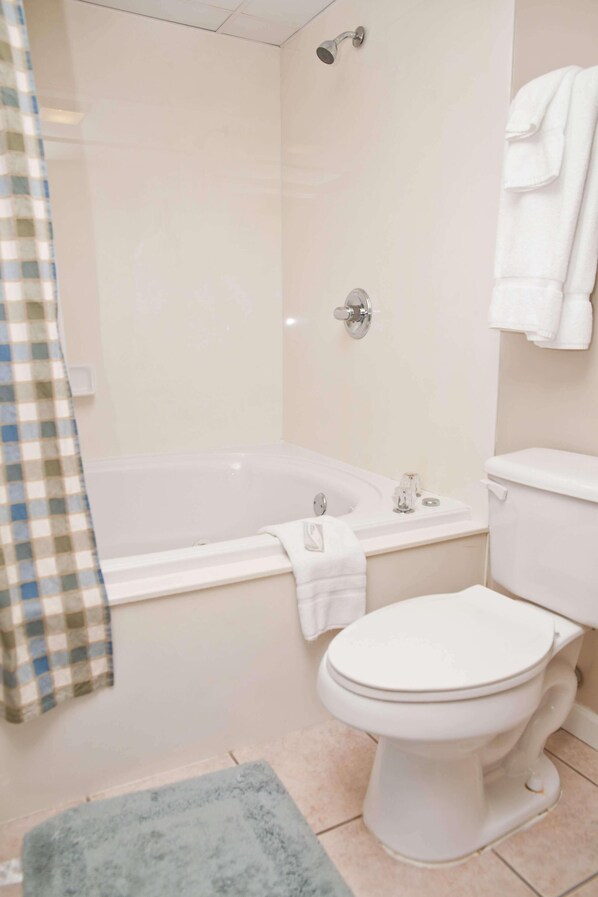 A bathroom with a bathtub, toilet, and a shower area.