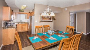 A dining area with a wooden table, chairs, and a chandelier. - Whispering Pines 541 (Pigeon Forge)