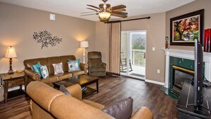 A living room with a sofa, armchair, coffee table, and fireplace. - Whispering Pines 541 (Pigeon Forge)