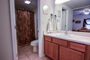 A bathroom with a white sink, wooden vanity, and a shower curtain. - Whispering Pines 611 (Pigeon Forge)