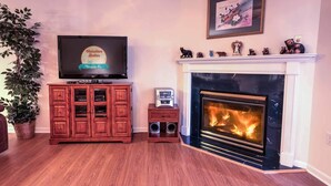 Un salon doté d’un téléviseur à écran plat, d’un meuble en bois, d’une cheminée et d’un tableau encadré accroché au mur.
