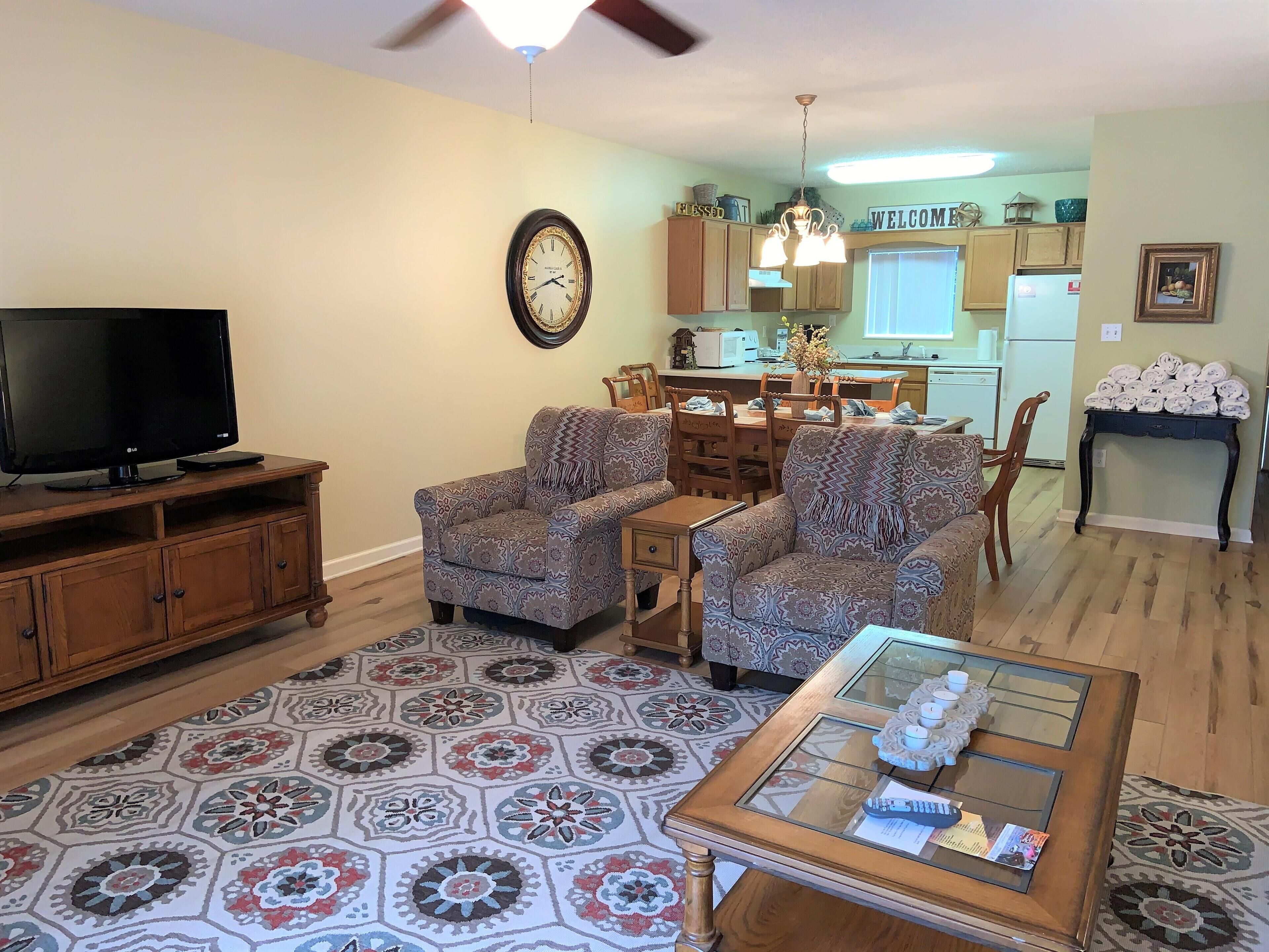 A living room with a TV, patterned armchairs, a coffee table, and a rug.