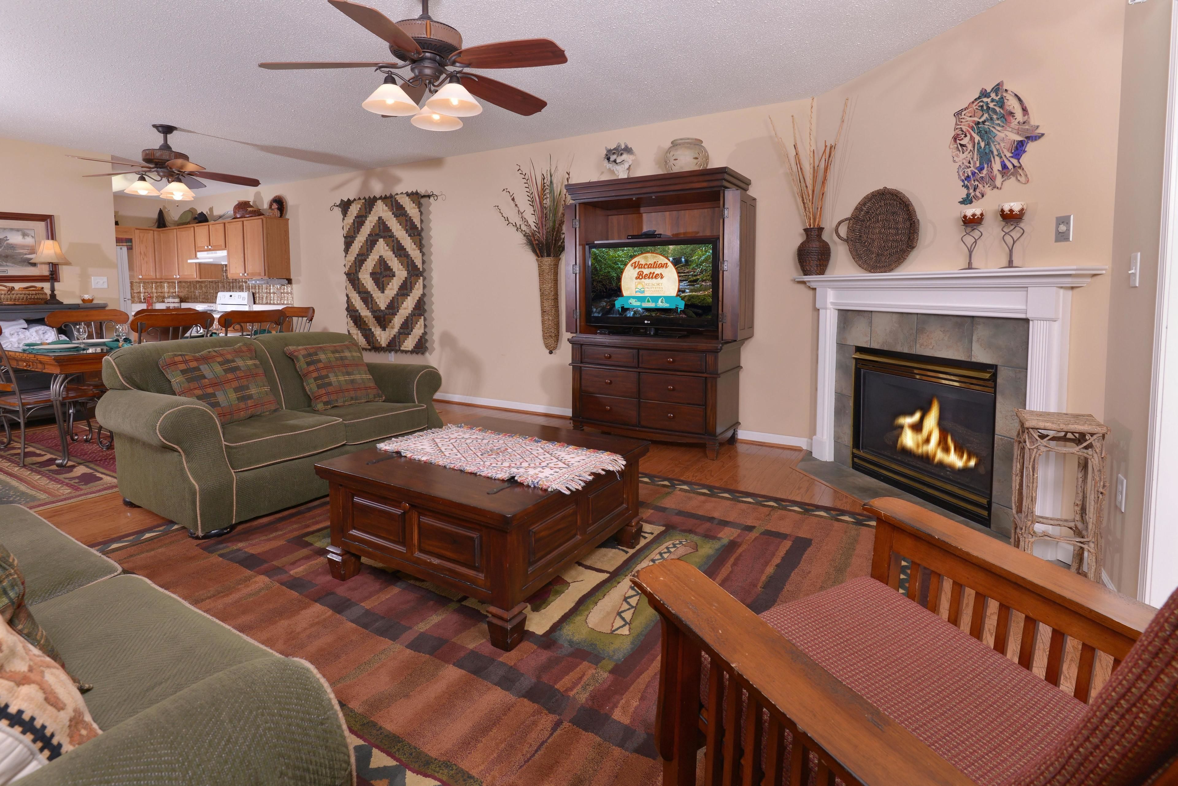 A living room with a fireplace, a television, and a dining area in the background.