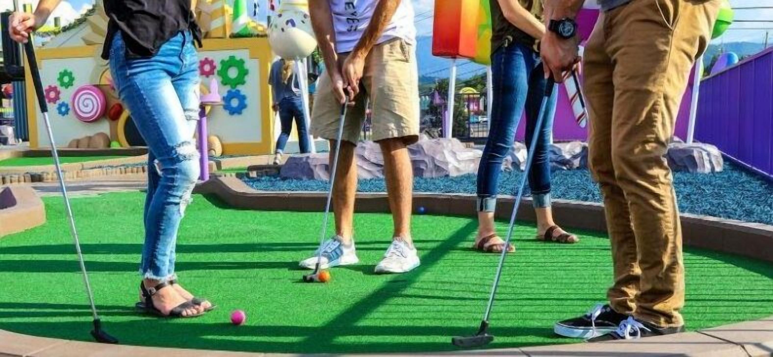 Pienoisgolfkenttä, jossa on vihreä keinonurmi, värikkäät maalitaulut ja pelaajat, joilla on yllään arkivaatteet.