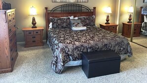 Un dormitorio con cama, dos mesitas de noche, cómoda, banco y espejo.