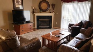 Una sala de estar con chimenea, sofás de cuero, una mesa de centro y un televisor.