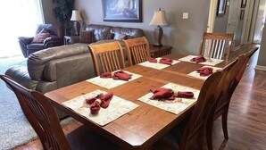 Un comedor con una mesa de madera dispuesta para seis personas, rodeada de sillas de madera.