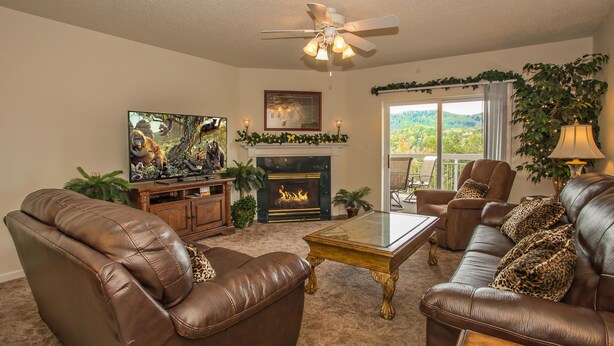 A living room with leather sofas, a fireplace, a television, and a balcony with a view. - Whispering Pines 643 (Pigeon Forge)