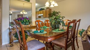 A dining area with a glass-top table, wooden chairs, and a chandelier. - Whispering Pines 643 (Pigeon Forge)