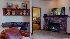 A living room with a stone fireplace, a television, and a dining area with chairs and a table. - Big Bear Resort 3002 (Pigeon Forge)