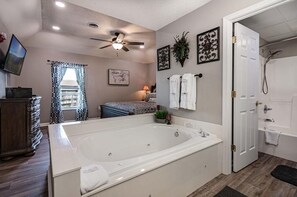 A modern bathroom with a large bathtub, a shower, and a vanity with a mirror. - Whispering Pines 654 (Pigeon Forge)