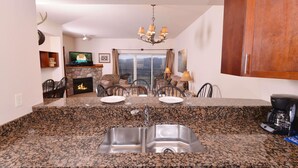 A kitchen with granite countertops, a double sink, and a dining area with chairs and a table. - 4002 Big Bear Resort (Pigeon Forge)