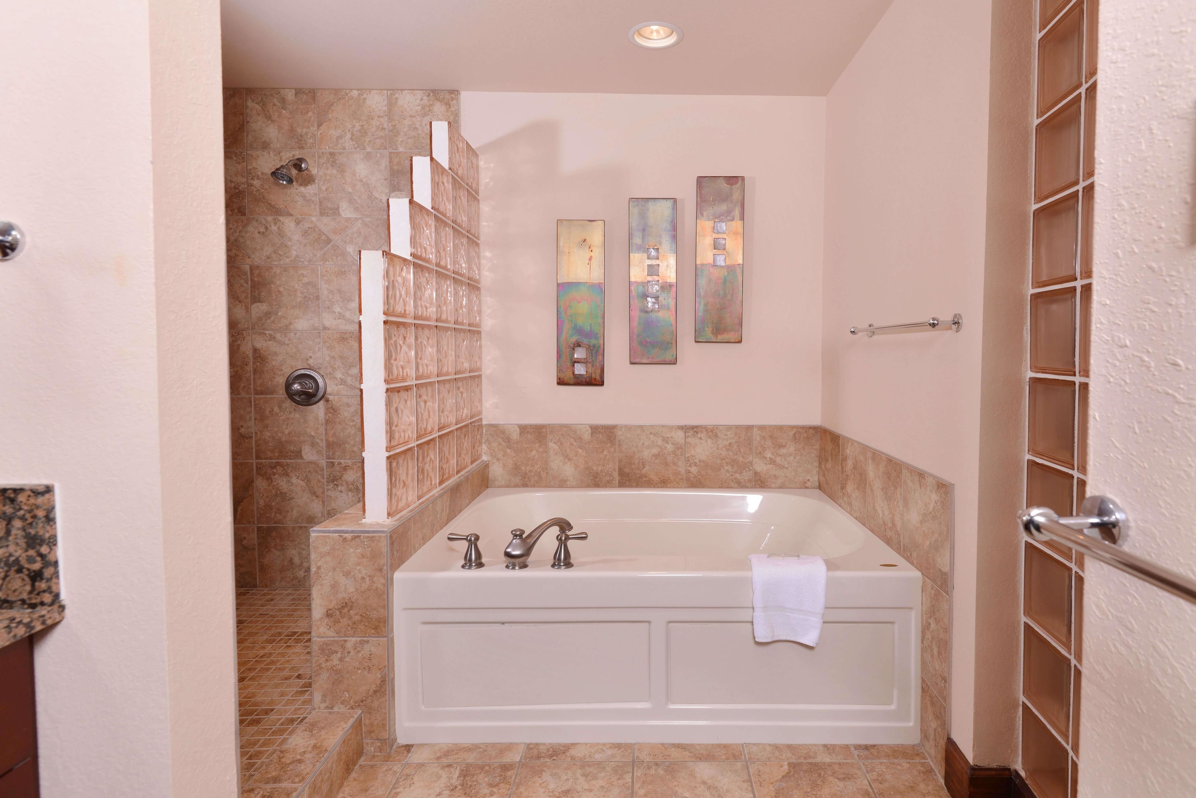 A bathroom with a large bathtub, a shower area, and a towel rack.