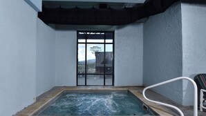A small indoor pool with a glass wall, a white safety railing, and a sign indicating hours of operation. - 4002 Big Bear Resort (Pigeon Forge)