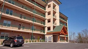 A multi-story hotel with balconies, a parking lot, and a distinctive orange building with a green roof. - 4002 Big Bear Resort (Pigeon Forge)