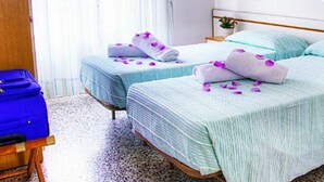 A hotel room with two beds, each with a blue and white striped bedspread, and a blue suitcase on a wooden chair. - Hotel Villa Iris (Rimini)
