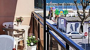 A balcony with a view of the beach, a stop sign, and parked cars. - Hotel Villa Iris (Rimini)