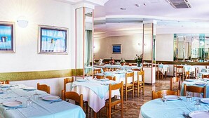 A restaurant with multiple tables set for dining, featuring a marble floor and light blue tablecloths. - Hotel Villa Iris (Rimini)